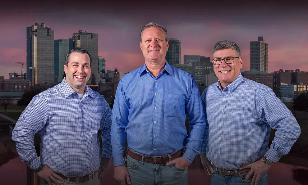 Anderson, Cummings & Drawhorn standing in front of a city skyline during sunset
