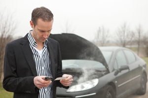 driver on phone with broken down car in background