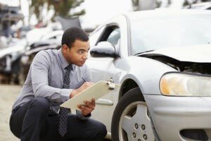 insurance inspector looking at damaged car