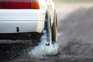 image of white car burning rubber