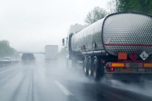 semi-truck on rainy highway next to cars