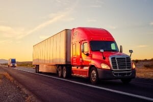 semi-truck with red cab speeding down a highway