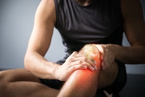 young man holding injured knee