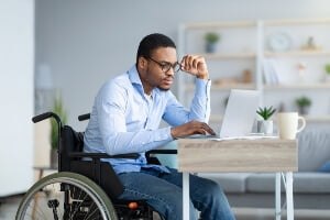 stock image: black male in wheelchair working on laptop
