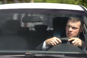irritated male driver looking in rearview mirror