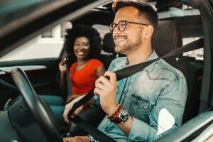 young multi-racial couple buckling up in car