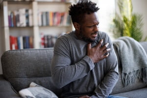 young black man clutching his chest in pain
