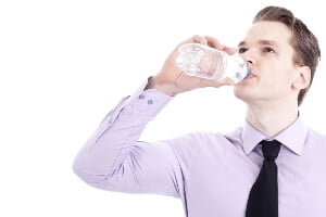 young businessman wearing a dress shirt and tie drinking bottled water