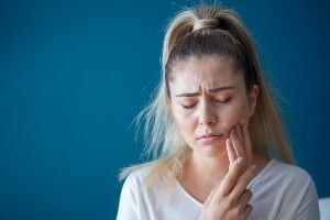 image of young woman holding her jaw in pain