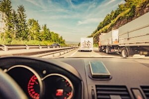 car riding behind and next to semi-trucks