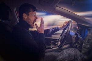 Young man yawning while driving at night