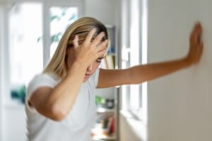 young woman feeling dizzy and holding wall to steady herself